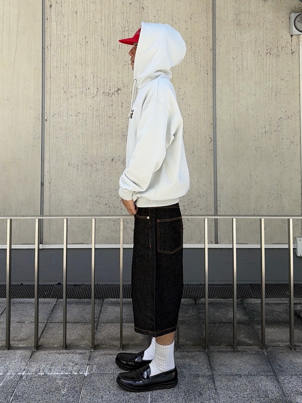 グレー系のパーカー、グリーン系のデニムパンツ、レッド系のキャップを着用したメンズの夏コーディネートの3枚目の写真
