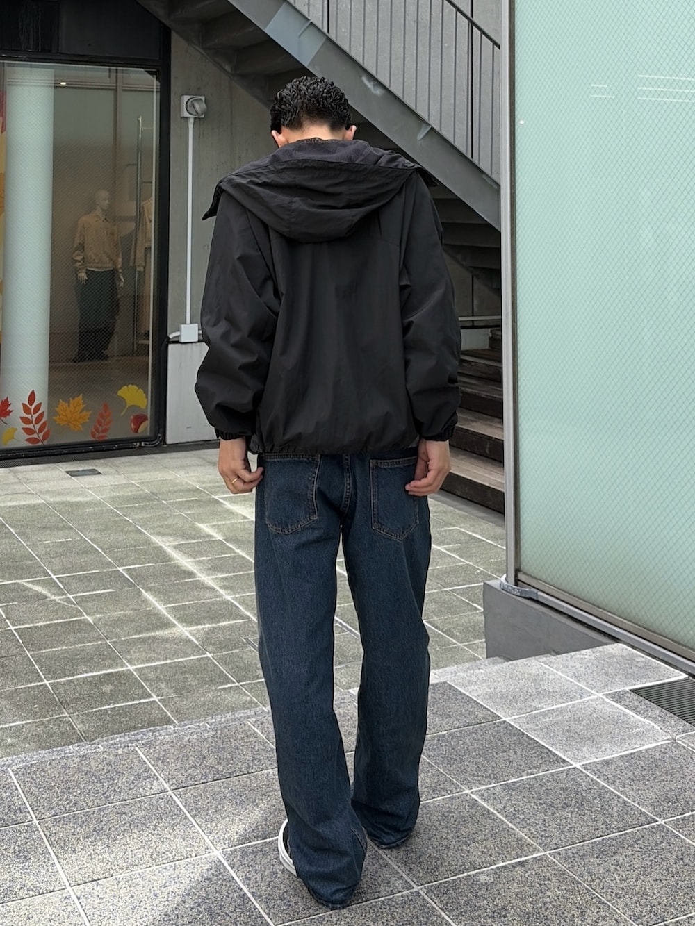 レッド系のナイロンジャケット、グレー系のスウェット、ブルー系のデニムパンツを着用したメンズの秋コーディネートの5枚目の写真