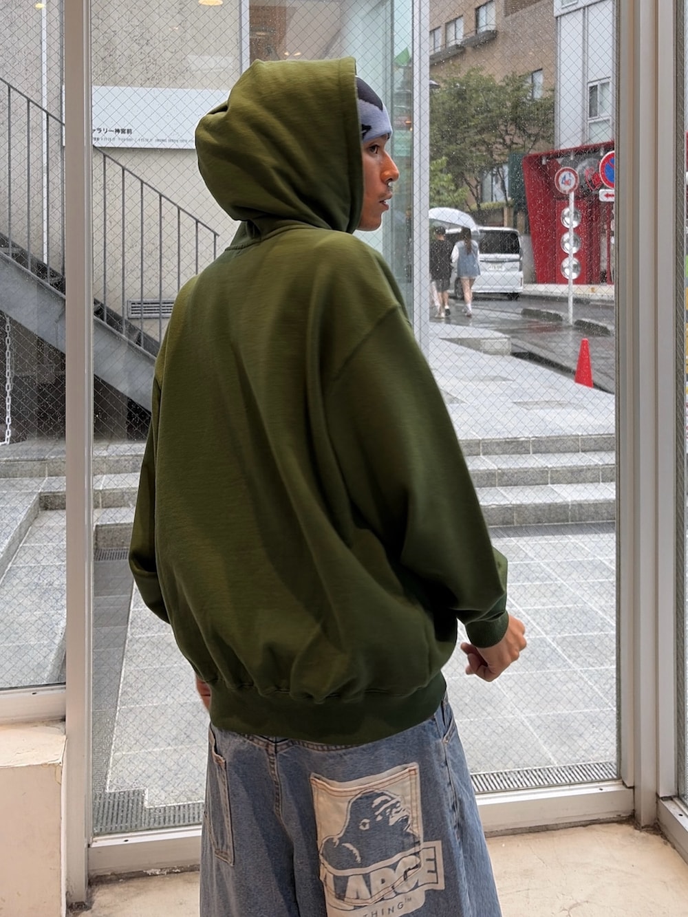 グリーン系のパーカー、グリーン系のデニムパンツ、ブルー系のキャップを着用したメンズの秋コーディネートの7枚目の写真