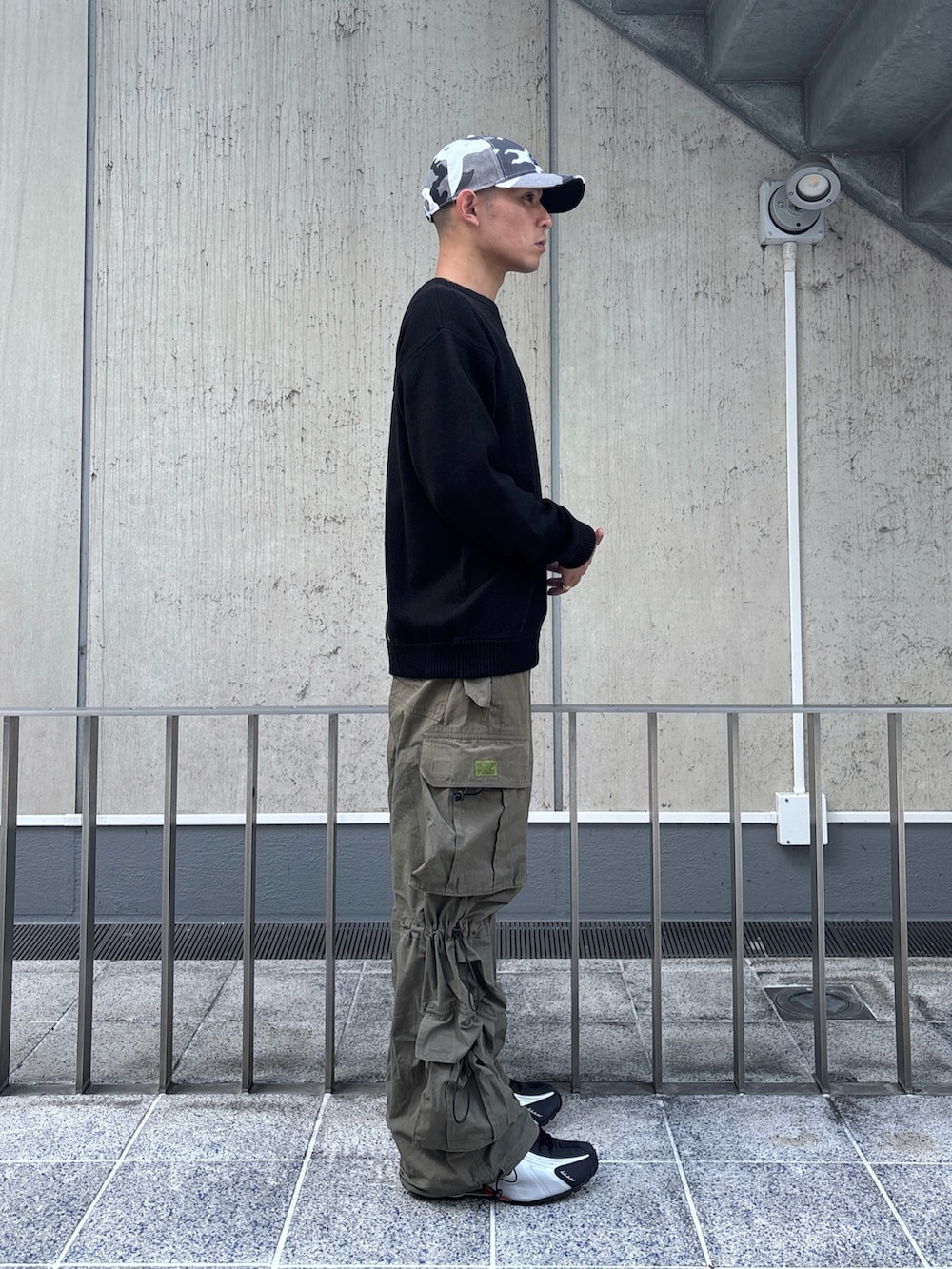 ブラック系のニット/セーター、グリーン系のカーゴパンツ、その他のキャップを着用したメンズの秋コーディネートの4枚目の写真