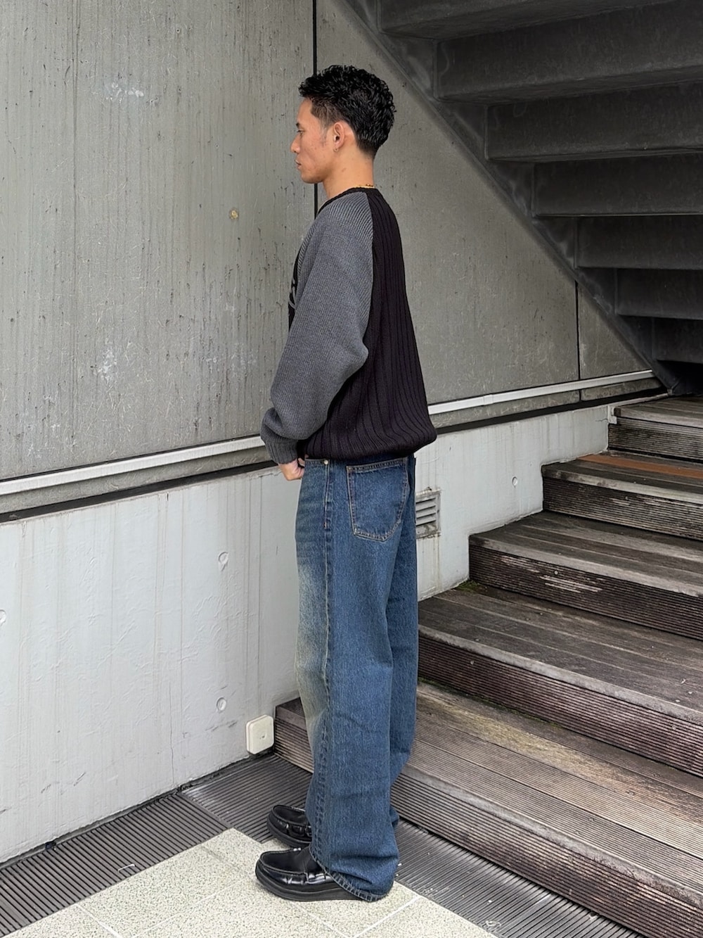 ブラック系のニット/セーター、ブルー系のデニムパンツを着用したメンズの秋コーディネートの2枚目の写真