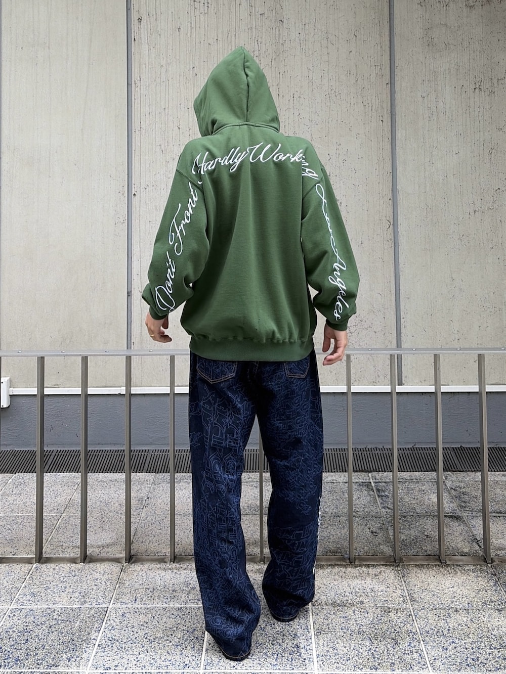 グリーン系のパーカー、ブルー系のデニムパンツ、レッド系のニットキャップ/ビーニーを着用したメンズの秋コーディネートの5枚目の写真
