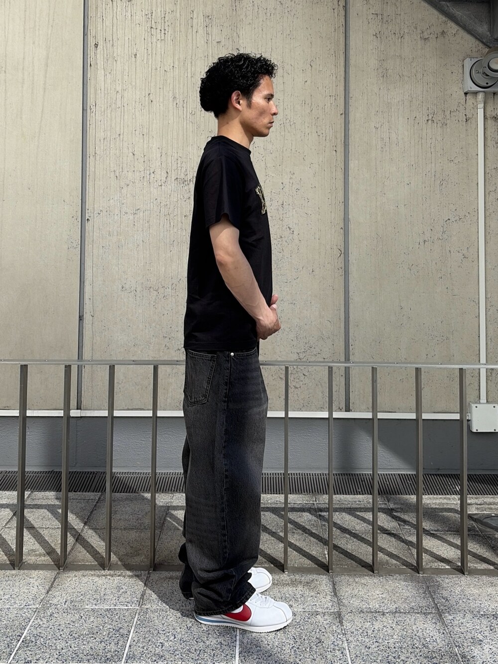 ブラック系のTシャツ/カットソー、ブルー系のデニムパンツを着用したメンズの春コーディネートの4枚目の写真