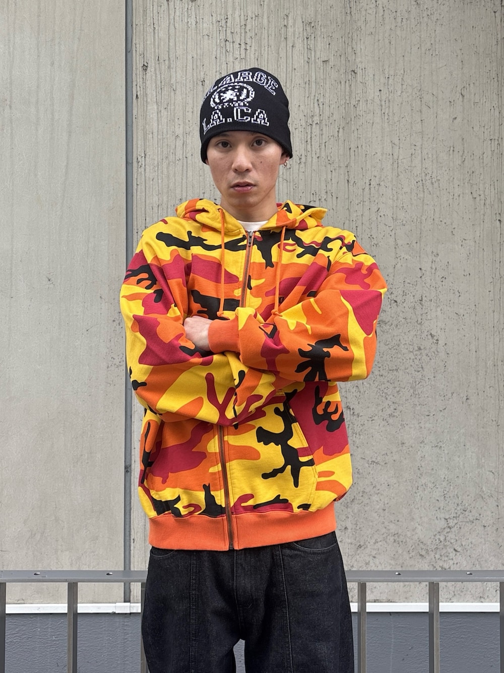 オレンジ系のパーカー、ブラック系のデニムパンツを着用したメンズの冬コーディネートの5枚目の写真