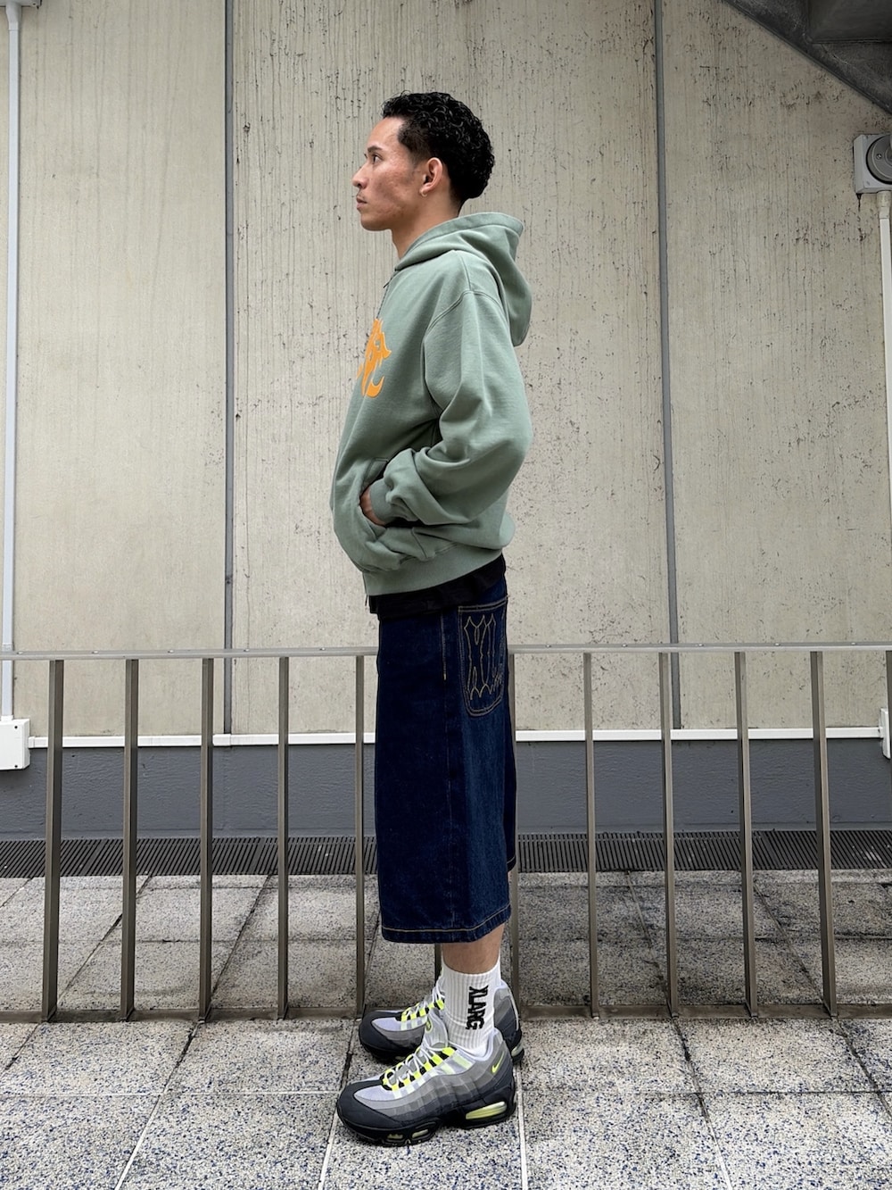 ピンク系のパーカー、ブルー系のデニムパンツを着用したメンズの春コーディネートの2枚目の写真