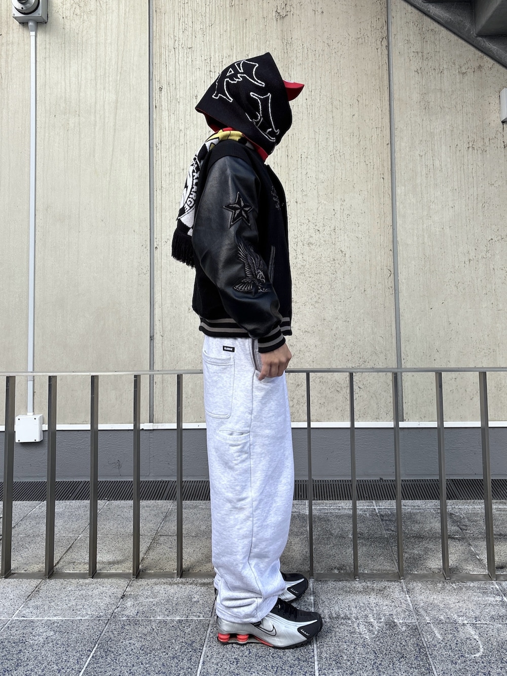 ブラック系のスタジャン、グレー系のスウェットパンツ、レッド系のキャップを着用したメンズの秋コーディネートの2枚目の写真