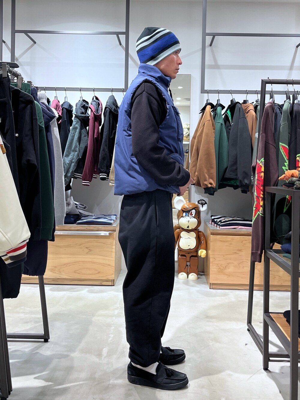 グレー系のスウェットパンツ、ブルー系のベスト、ブラック系のニット/セーターを着用したメンズの秋コーディネートの4枚目の写真