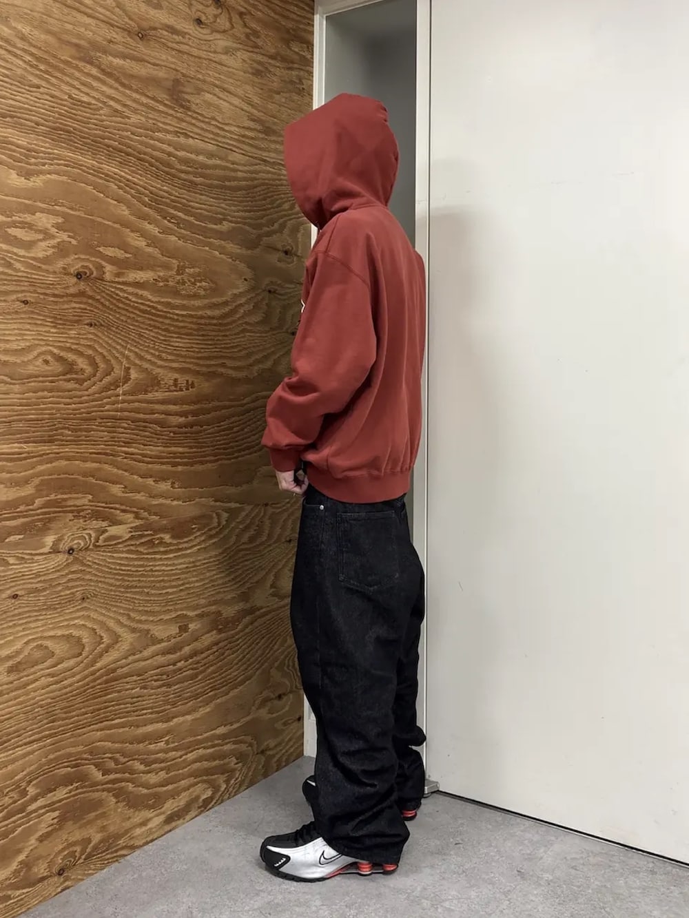 レッド系のパーカー、ブラック系のデニムパンツを着用したメンズの冬コーディネートの3枚目の写真