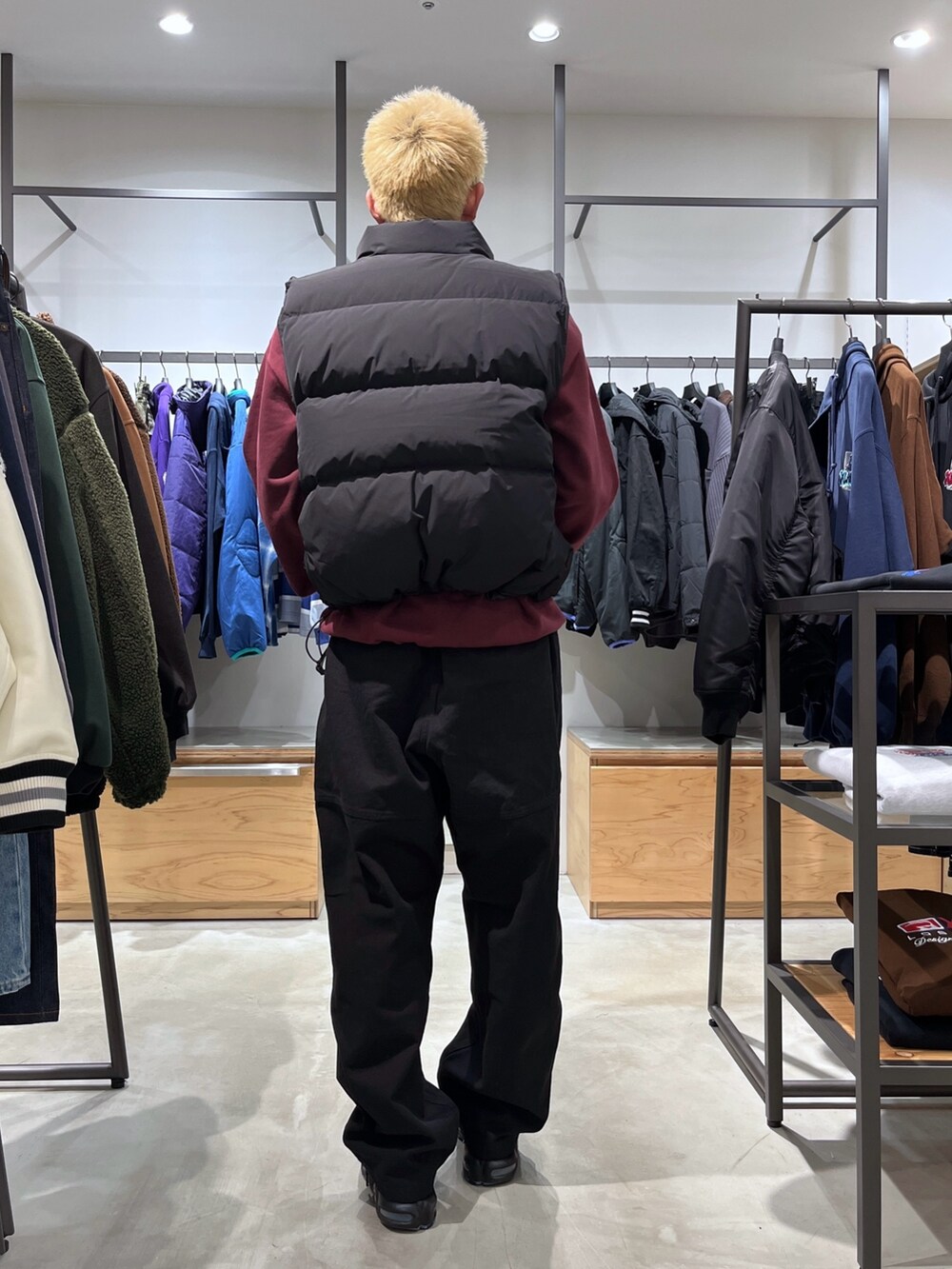 レッド系のスウェット、ブラック系のその他パンツ、ブラック系のダウンベストを着用したメンズの秋コーディネートの8枚目の写真