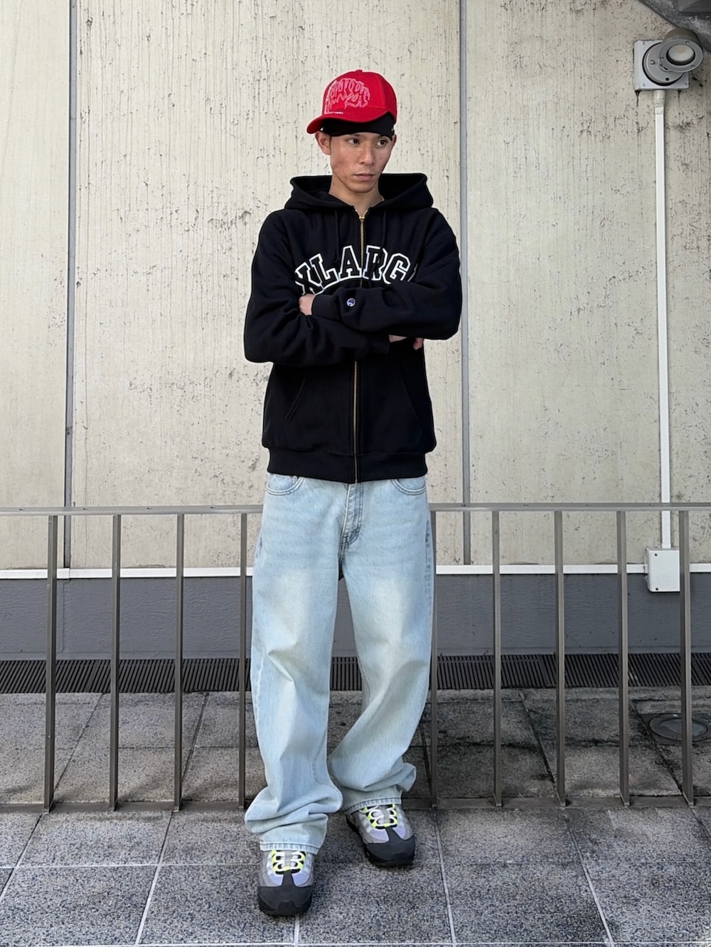 ブラック系のパーカー、ブルー系のデニムパンツ、レッド系のキャップを着用したメンズの秋コーディネートの2枚目の写真