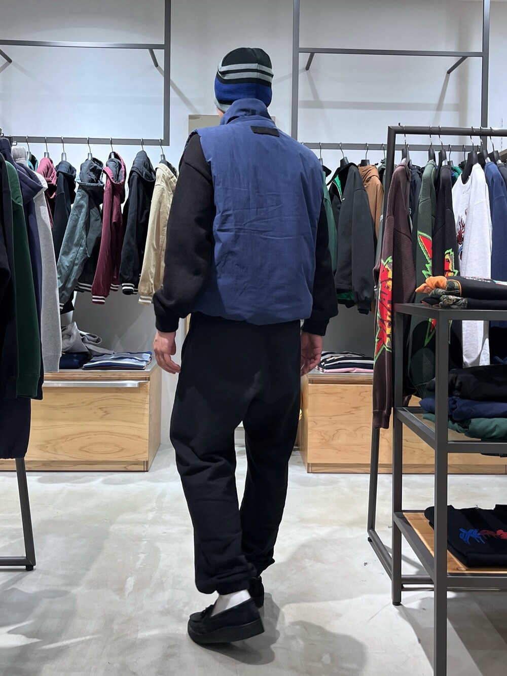 グレー系のスウェットパンツ、ブルー系のベスト、ブラック系のニット/セーターを着用したメンズの秋コーディネートの3枚目の写真