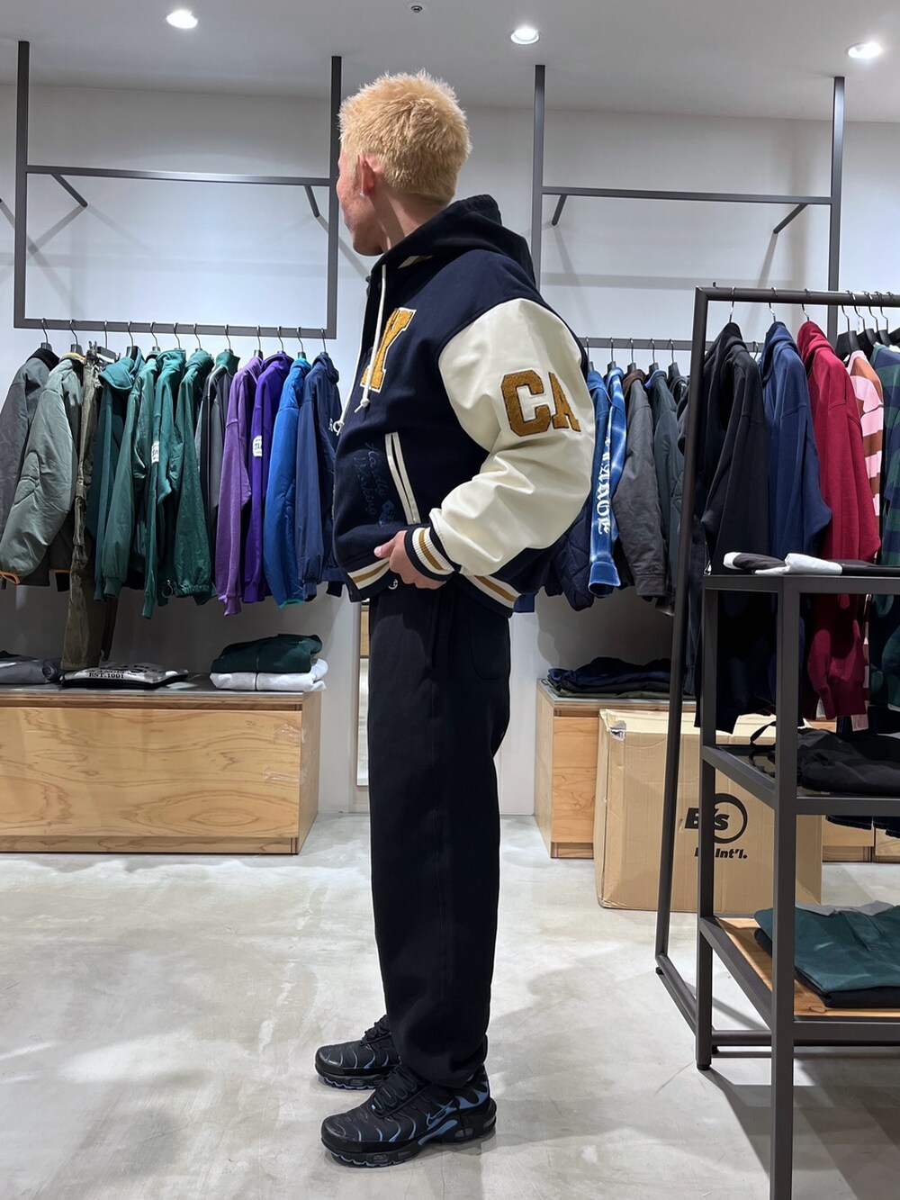 ブルー系のスタジャン、ブラック系のスウェットパンツ、ブラック系のパーカーを着用したメンズの秋コーディネートの2枚目の写真