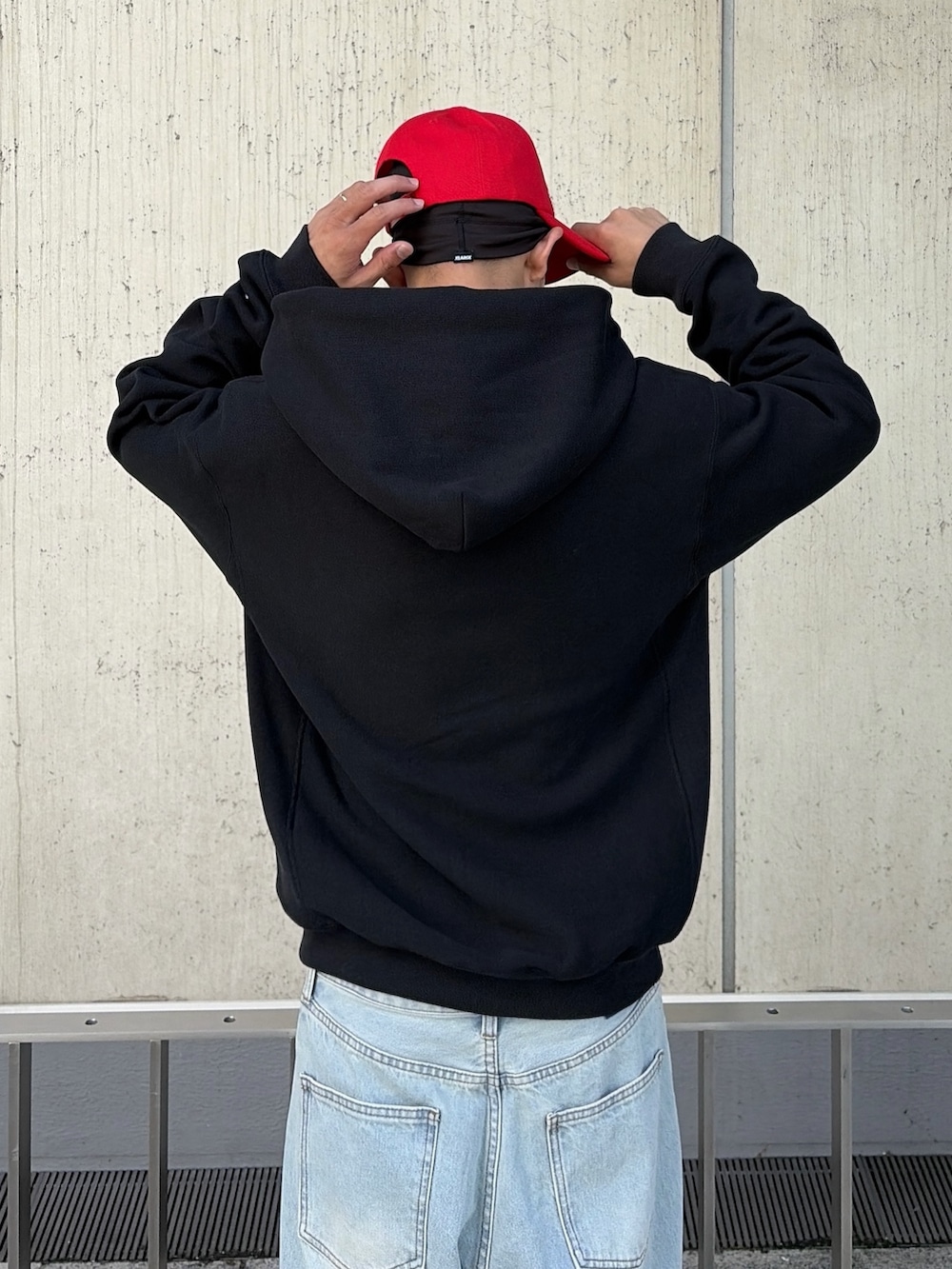 ブラック系のパーカー、ブルー系のデニムパンツ、レッド系のキャップを着用したメンズの秋コーディネートの9枚目の写真