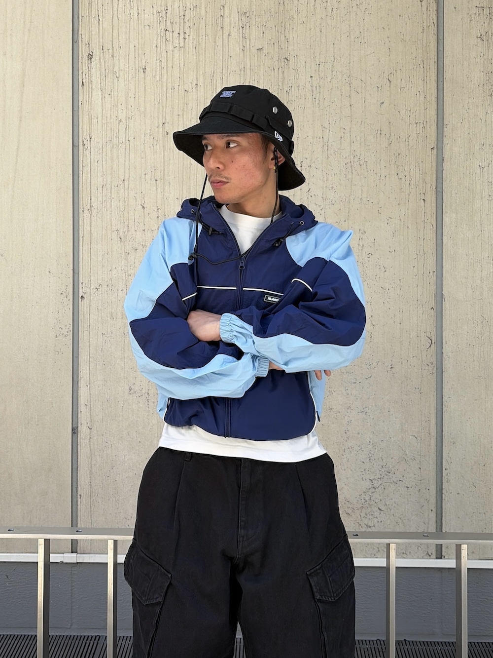 ブルー系のナイロンジャケット、ブラック系のカーゴパンツ、ブラック系のハットを着用したメンズの春コーディネートの6枚目の写真