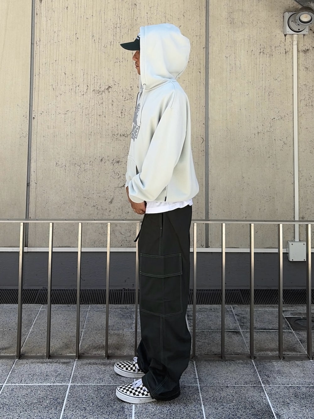 ブラック系のパーカー、グリーン系のカーゴパンツ、グリーン系のキャップを着用したメンズの夏コーディネートの3枚目の写真