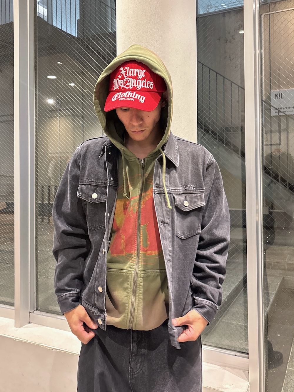 ブラック系のデニムジャケット、グリーン系のパーカー、ブラウン系のデニムパンツを着用したメンズの秋コーディネートの4枚目の写真