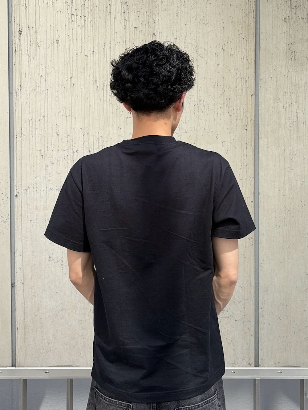 ブラック系のTシャツ/カットソー、ブルー系のデニムパンツを着用したメンズの春コーディネートの7枚目の写真