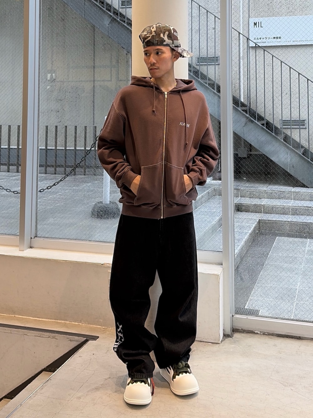 ブラウン系のパーカー、ブルー系のデニムパンツ、ブラック系のキャップを着用したメンズの秋コーディネートの3枚目の写真