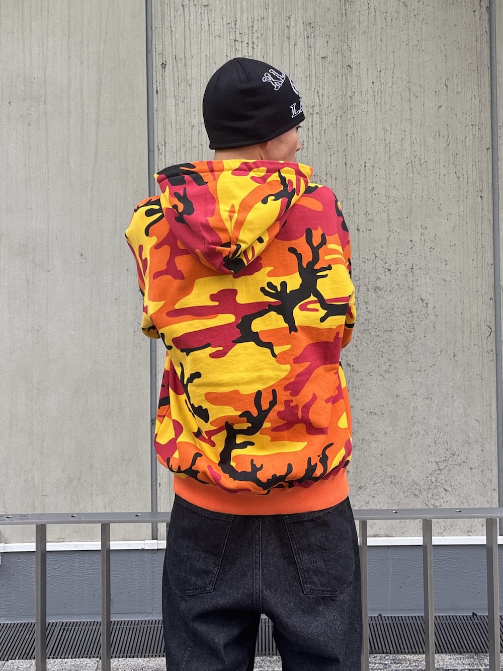 オレンジ系のパーカー、ブラック系のデニムパンツを着用したメンズの冬コーディネートの7枚目の写真