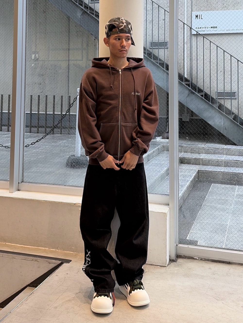 ブラウン系のパーカー、ブルー系のデニムパンツ、ブラック系のキャップを着用したメンズの秋コーディネートの2枚目の写真