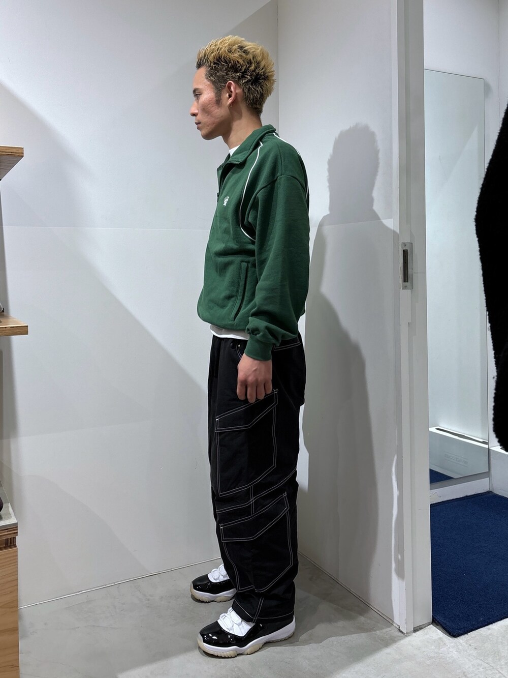 グリーン系のスウェット、ブラック系のカーゴパンツを着用したメンズの冬コーディネートの2枚目の写真