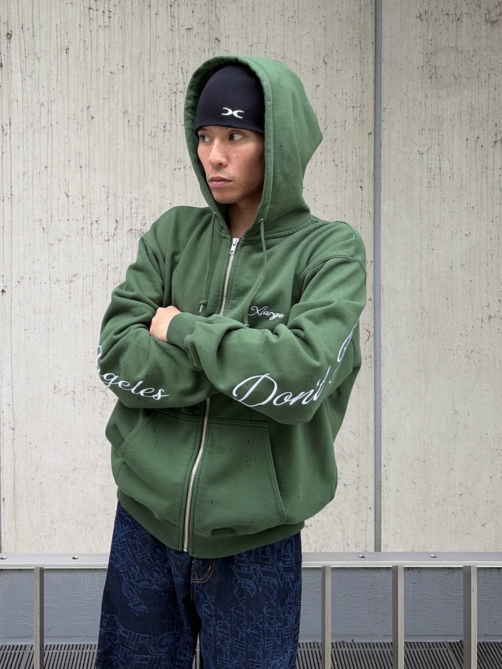 グリーン系のパーカー、ブルー系のデニムパンツ、レッド系のニットキャップ/ビーニーを着用したメンズの秋コーディネートの7枚目の写真