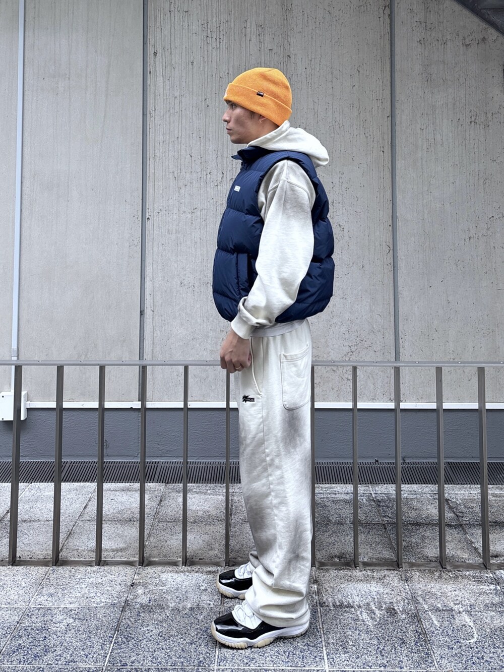 ブルー系のベスト、ホワイト系のパーカー、ホワイト系のスウェットパンツを着用したメンズの秋コーディネートの2枚目の写真