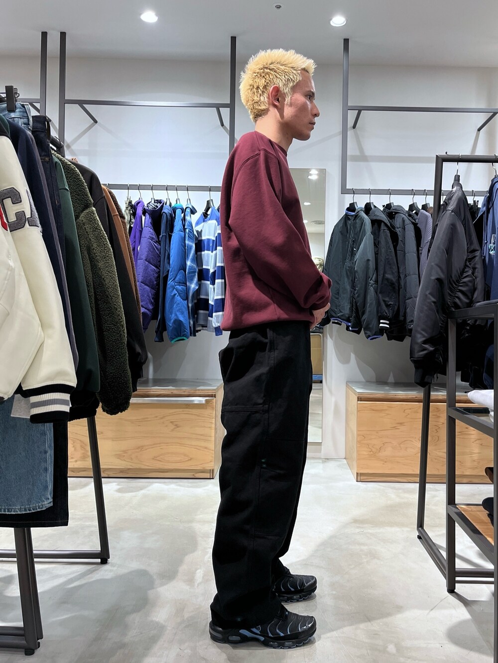 レッド系のスウェット、ブラック系のその他パンツ、ブラック系のダウンベストを着用したメンズの秋コーディネートの3枚目の写真