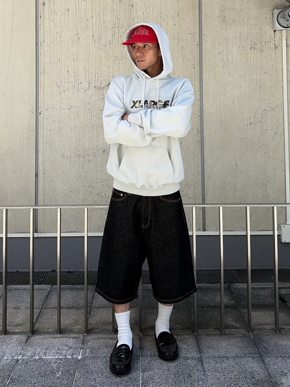 グレー系のパーカー、グリーン系のデニムパンツ、レッド系のキャップを着用したメンズの夏コーディネートの2枚目の写真