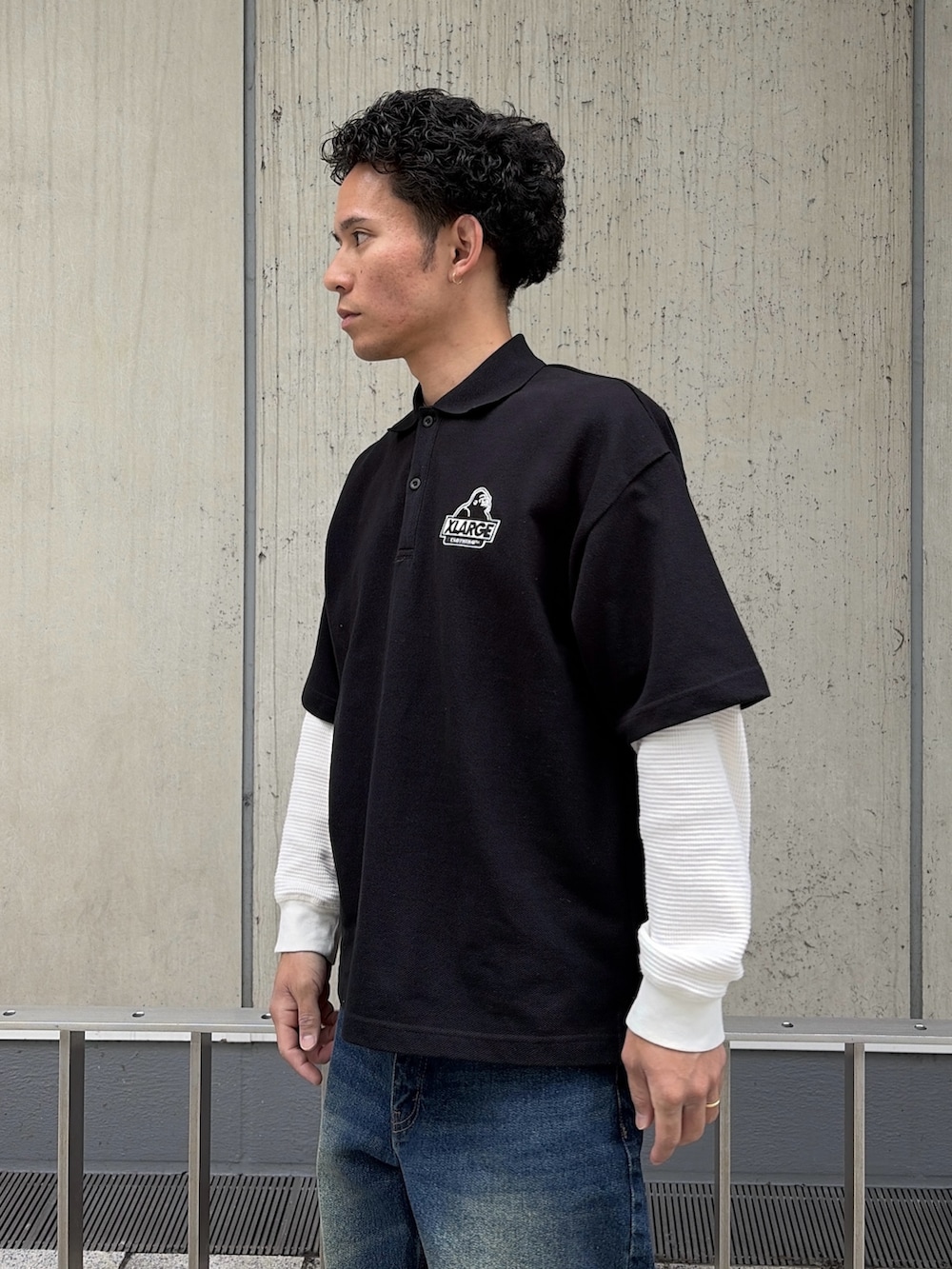 ホワイト系のTシャツ/カットソー、ブラック系のポロシャツ、ブルー系のデニムパンツを着用したメンズの春コーディネートの6枚目の写真