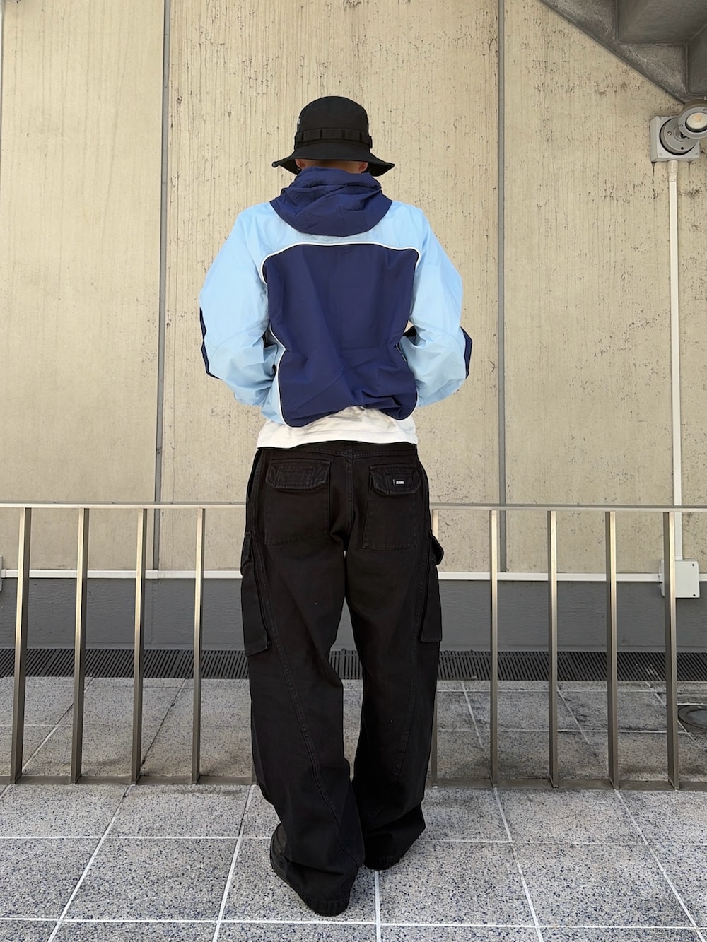 ブルー系のナイロンジャケット、ブラック系のカーゴパンツ、ブラック系のハットを着用したメンズの春コーディネートの4枚目の写真
