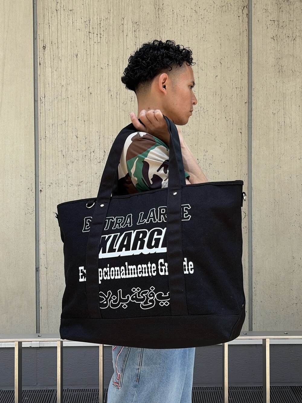 その他のTシャツ/カットソー、ブルー系のデニムパンツ、ブラック系のトートバッグを着用したメンズの夏コーディネートの7枚目の写真