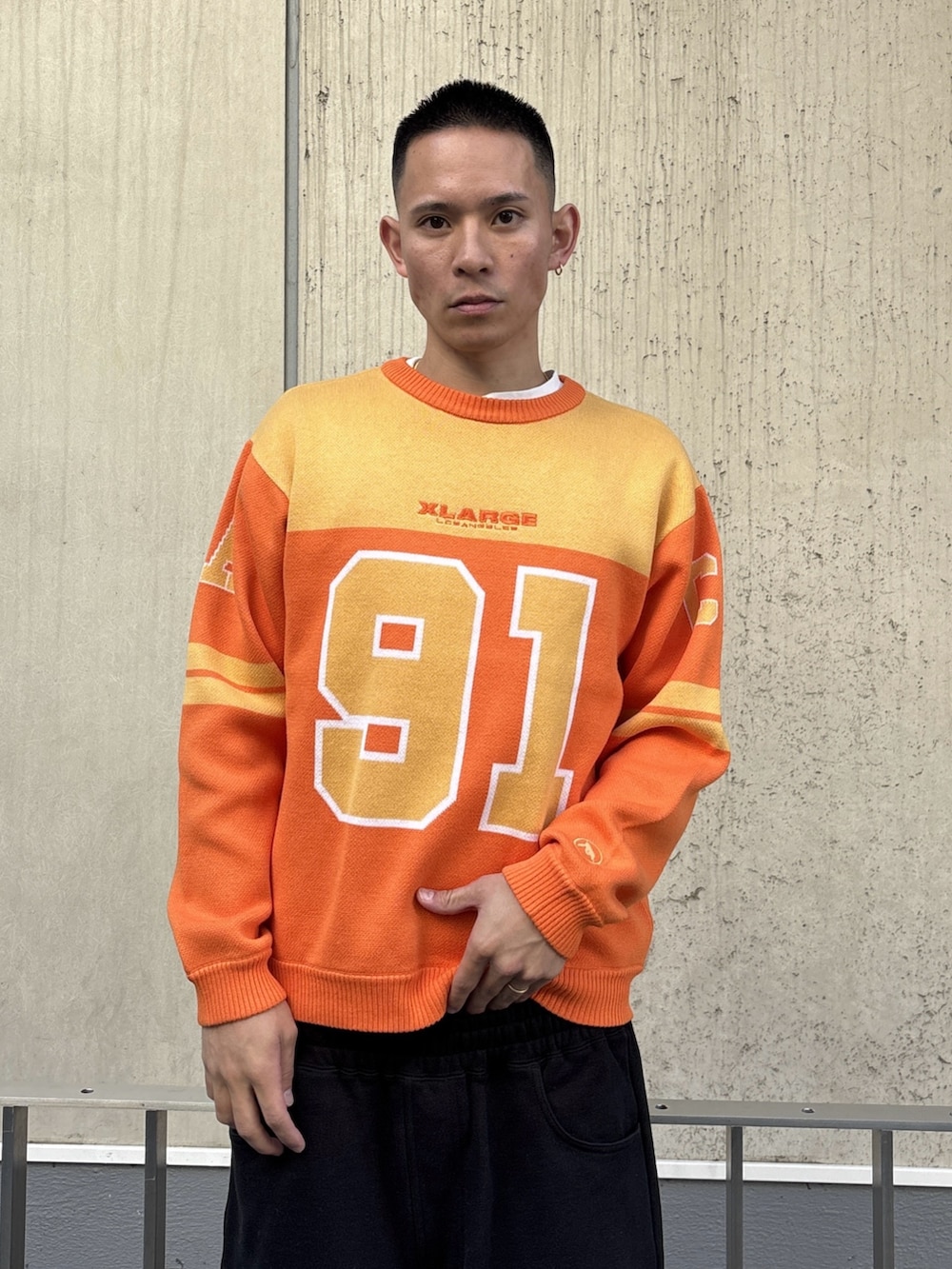 オレンジ系のニット/セーター、グレー系のスウェットパンツを着用したメンズの冬コーディネートの5枚目の写真