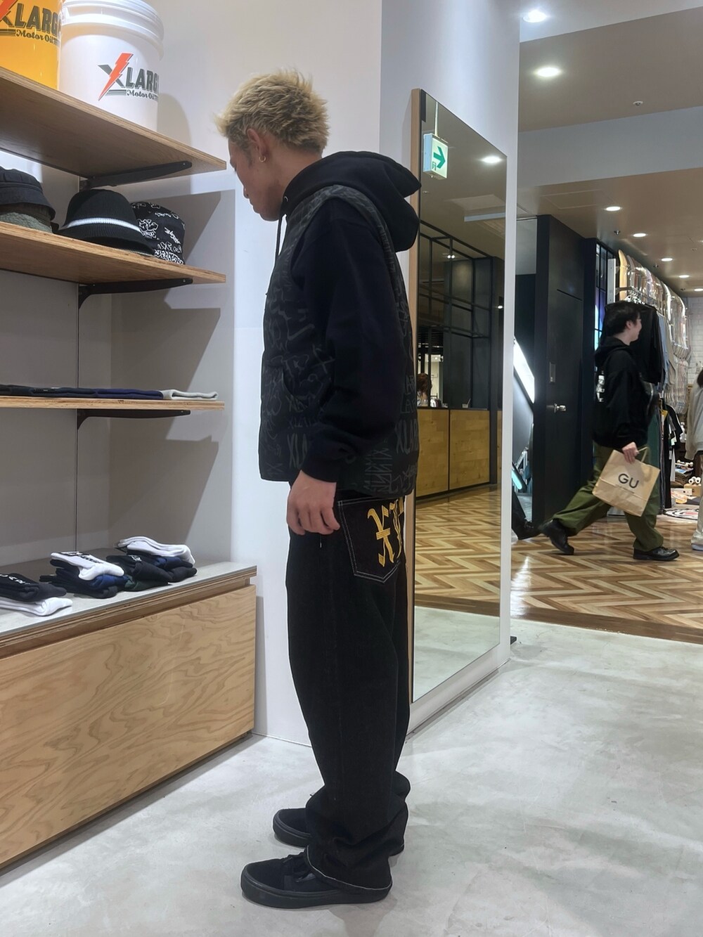 ブラック系のベスト、ブラック系のパーカー、ブラック系のデニムパンツを着用したメンズの秋コーディネートの2枚目の写真