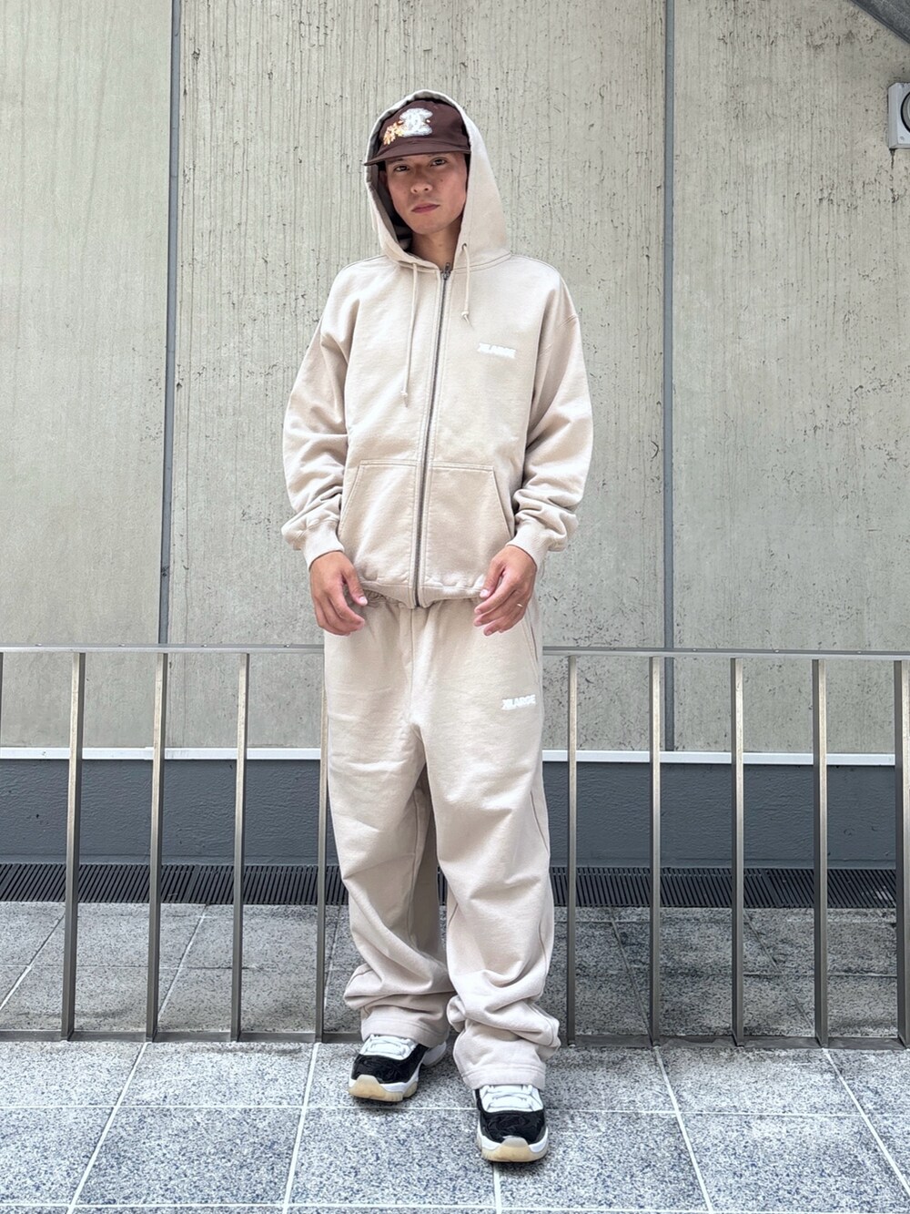 ベージュ系のスウェットパンツ、ベージュ系のパーカー、ブラウン系のキャップを着用したメンズの秋コーディネートの2枚目の写真