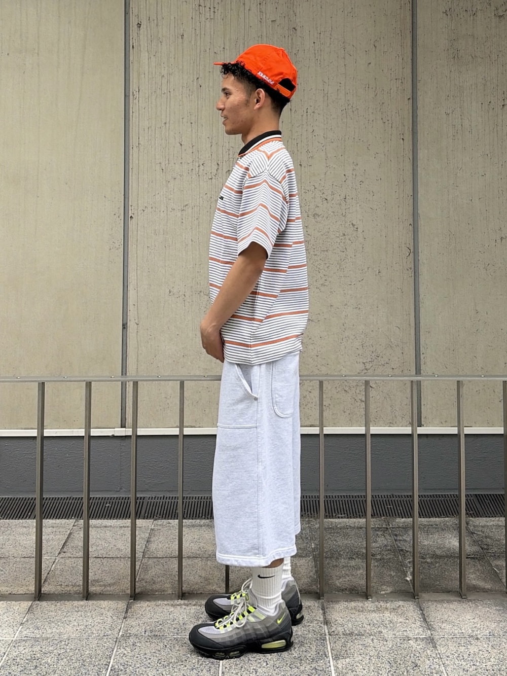 グレー系のスウェットパンツ、グレー系のTシャツ/カットソー、オレンジ系のキャップを着用したメンズの夏コーディネートの2枚目の写真