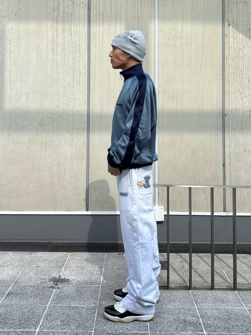 グレー系のスウェットパンツ、ブルー系のブルゾン、ブラック系のニットキャップ/ビーニーを着用したメンズの秋コーディネートの3枚目の写真