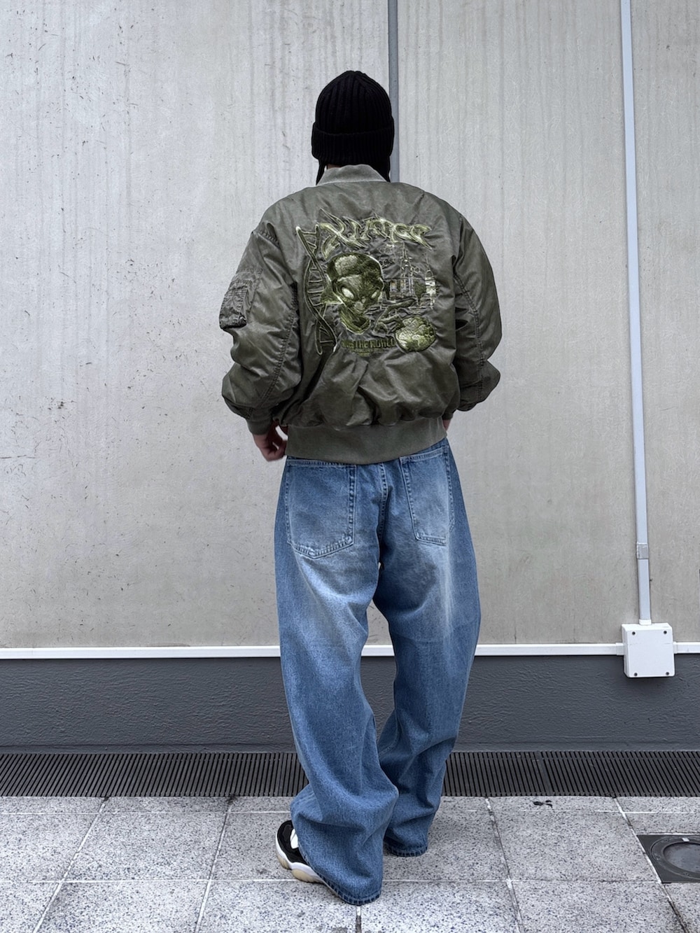 ブラック系のMA-1、ブルー系のデニムパンツ、ブラック系のニットキャップ/ビーニーを着用したメンズの秋コーディネートの4枚目の写真