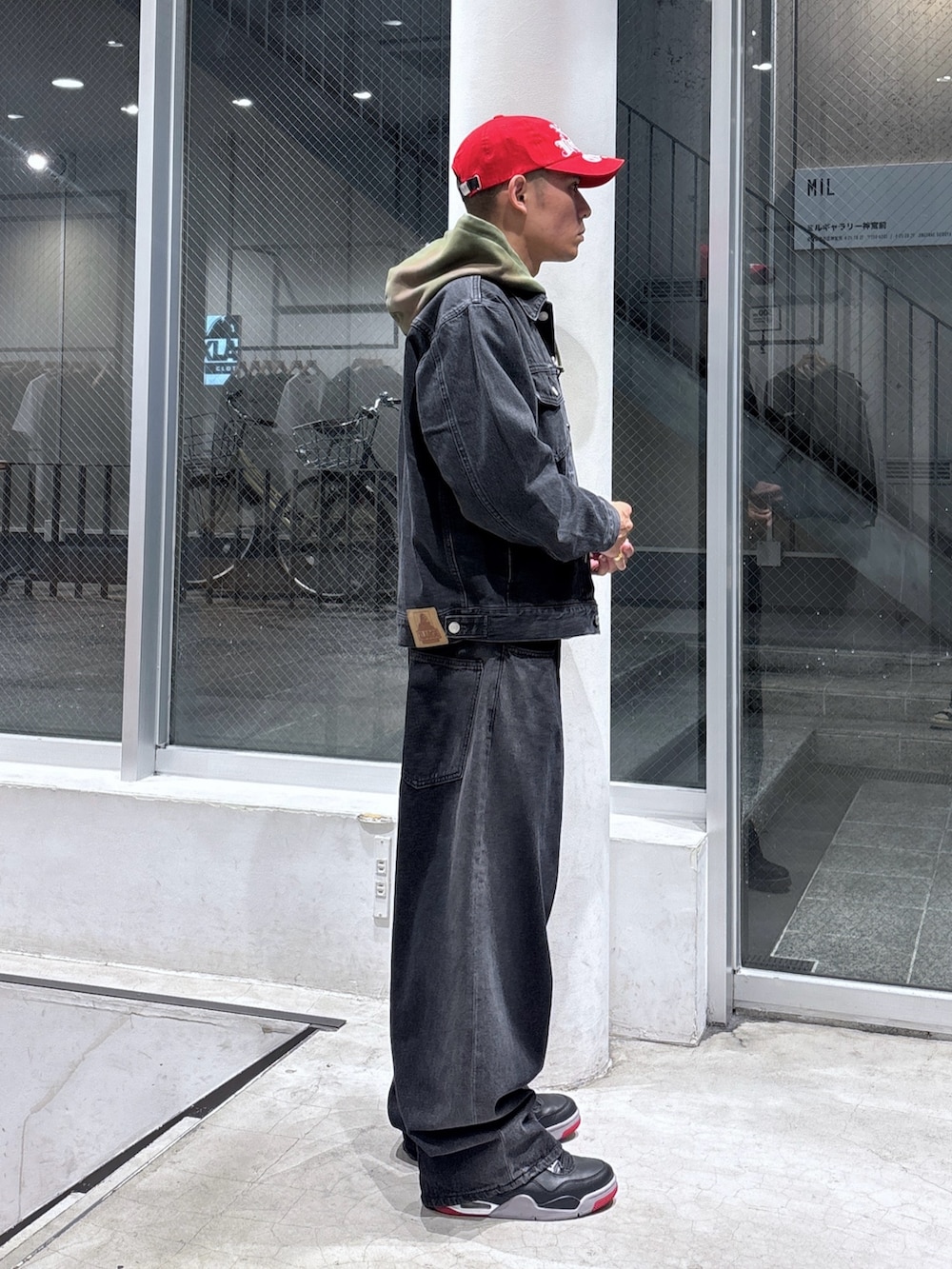 ブラック系のデニムジャケット、グリーン系のパーカー、ブラウン系のデニムパンツを着用したメンズの秋コーディネートの3枚目の写真