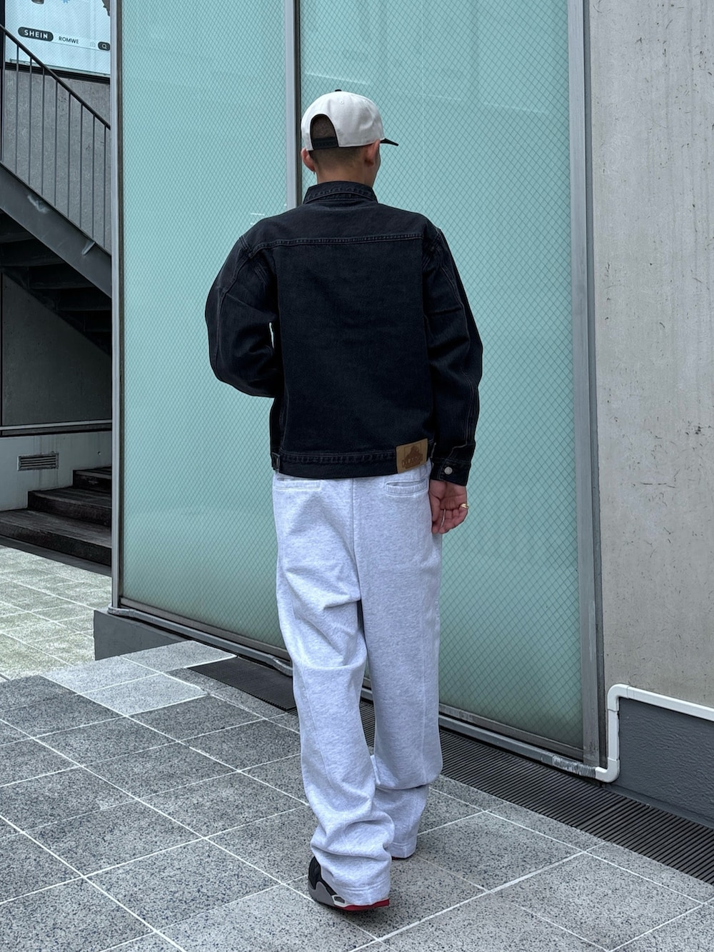 ブラック系のデニムジャケット、グレー系のスウェットパンツ、ホワイト系のキャップを着用したメンズの秋コーディネートの5枚目の写真