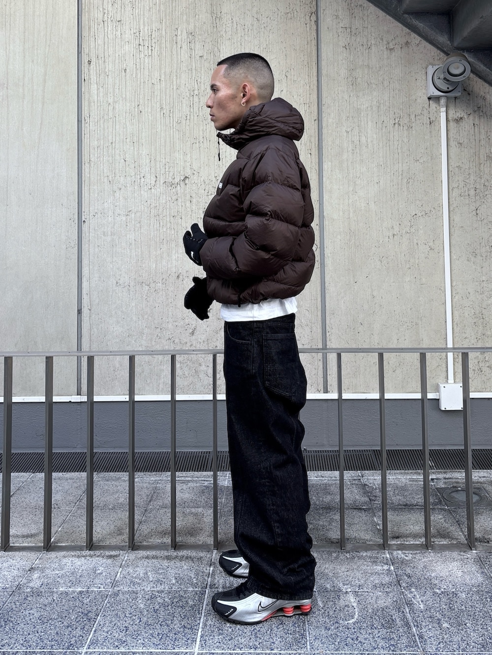 ブラウン系のダウンジャケット/コート、ブラック系のデニムパンツ、ブラック系の手袋を着用したメンズの秋コーディネートの2枚目の写真