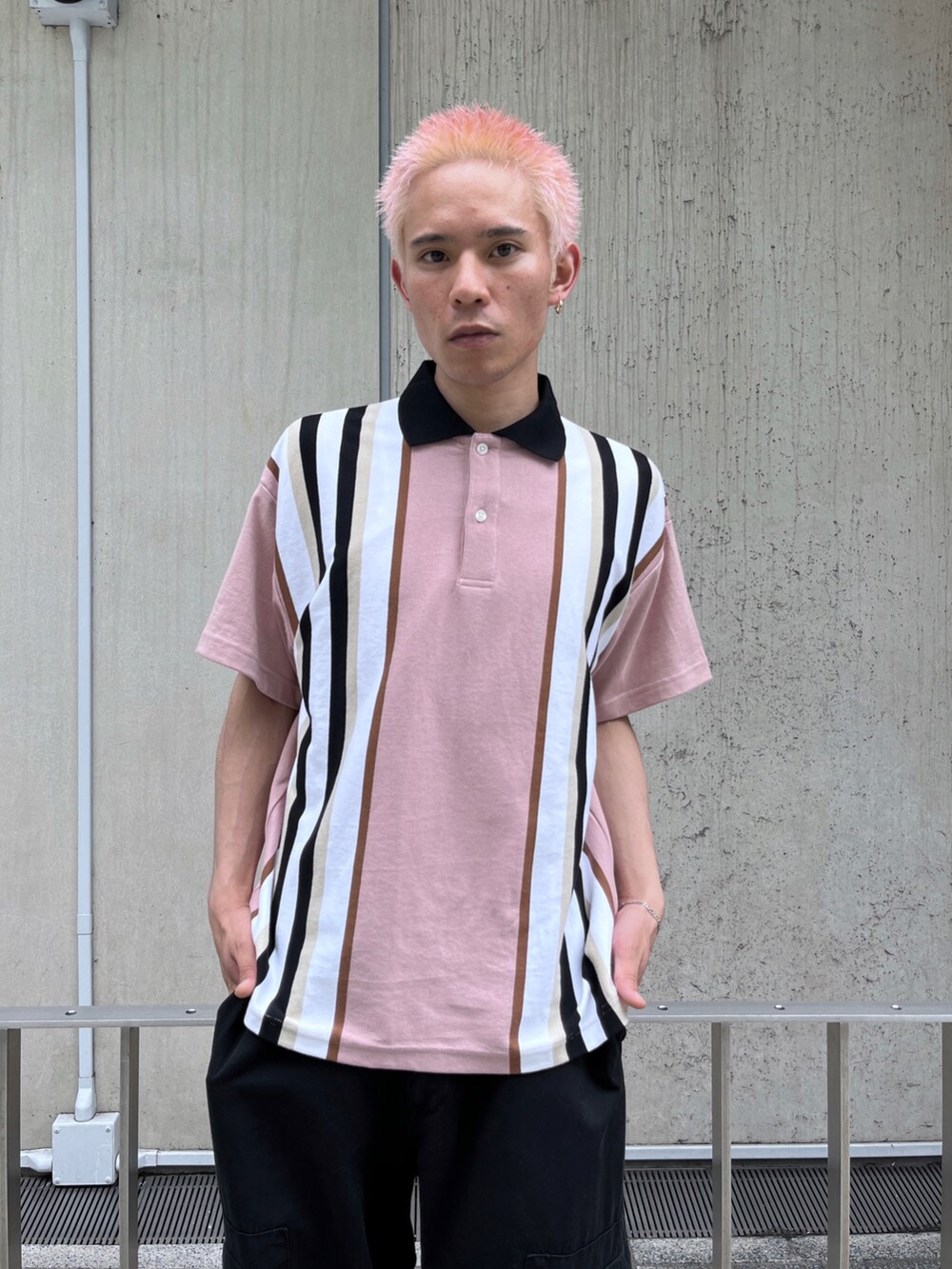 ピンク系のポロシャツ、ブラック系のカーゴパンツを着用したメンズの春コーディネートの4枚目の写真