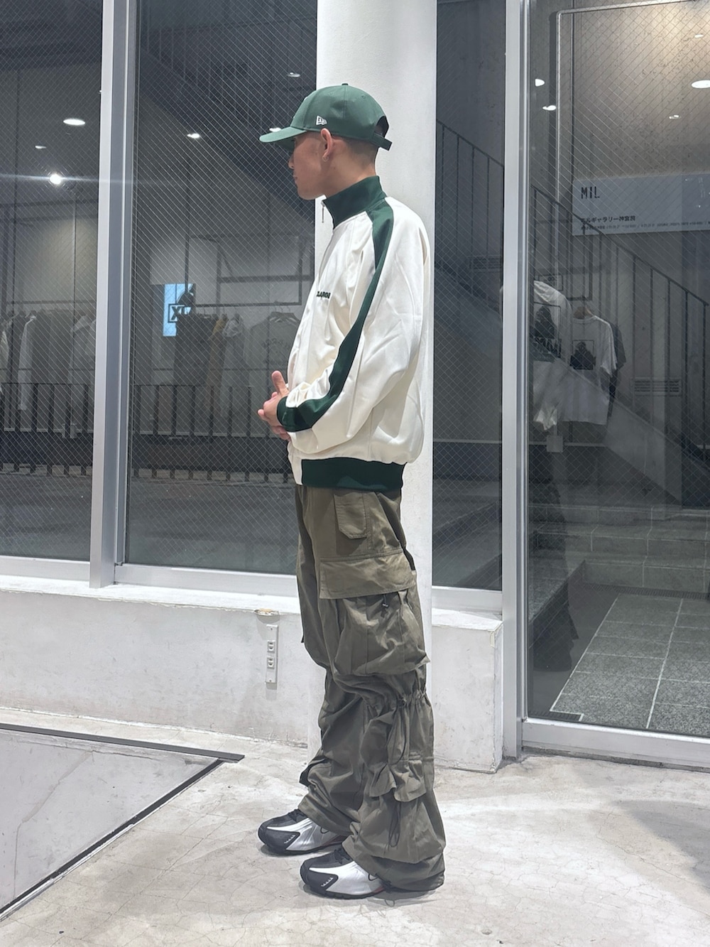 ホワイト系のブルゾン、グリーン系のカーゴパンツ、グリーン系のキャップを着用したメンズの秋コーディネートの2枚目の写真