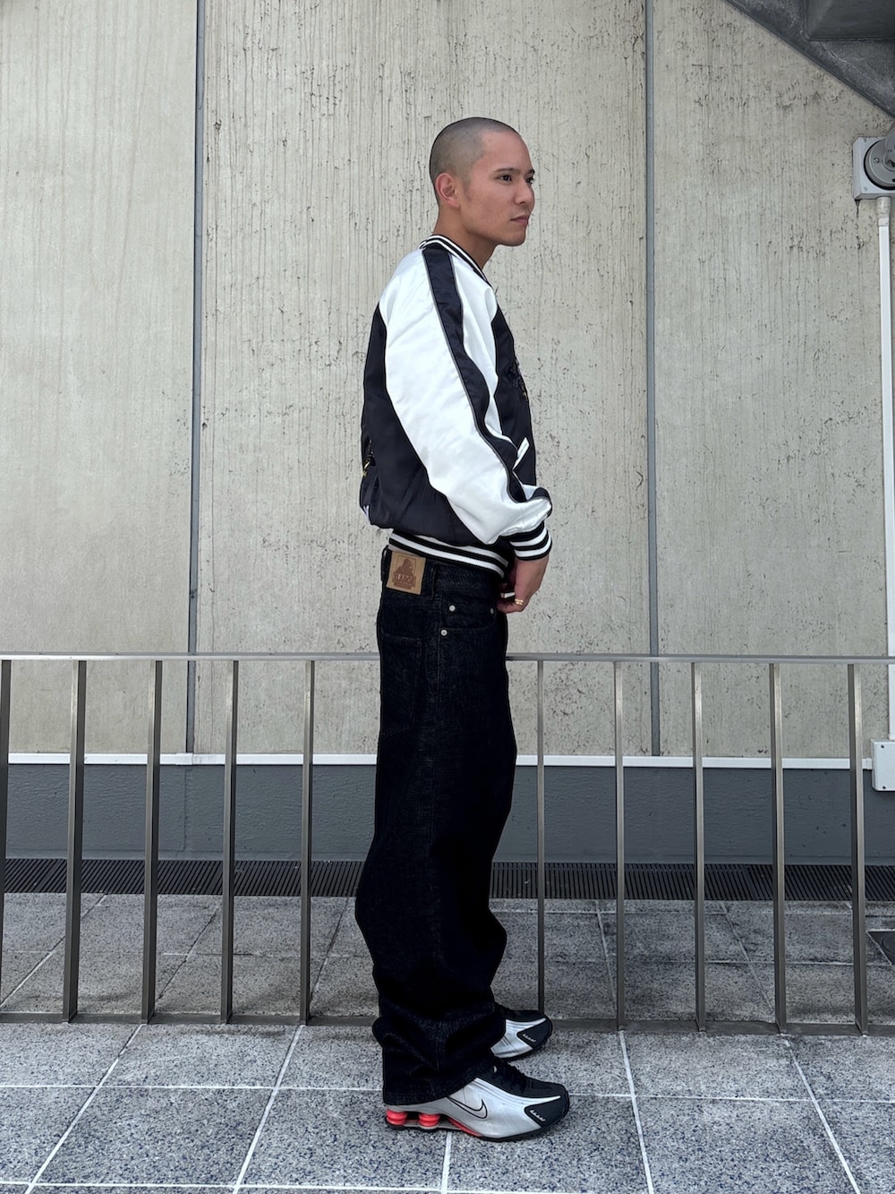 ブラック系のスカジャン、ブラック系のデニムパンツを着用したメンズの秋コーディネートの4枚目の写真