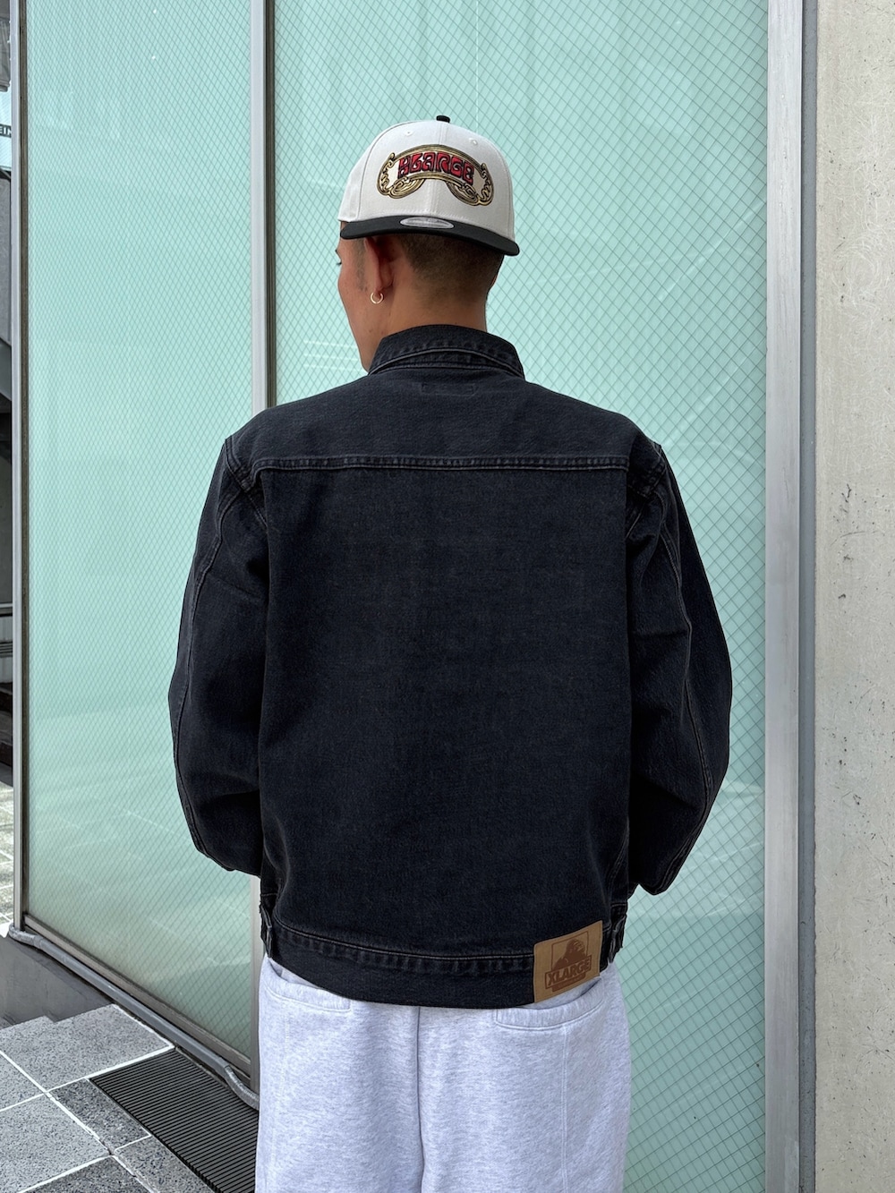 ブラック系のデニムジャケット、グレー系のスウェットパンツ、ホワイト系のキャップを着用したメンズの秋コーディネートの9枚目の写真