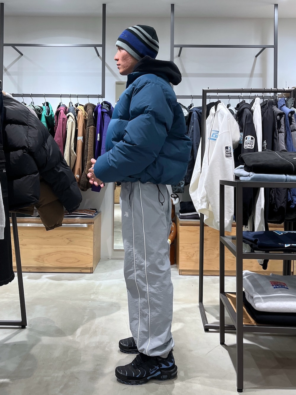 ブルー系のダウンジャケット/コート、グレー系のその他パンツ、ブラック系のニットキャップ/ビーニーを着用したメンズの秋コーディネートの2枚目の写真