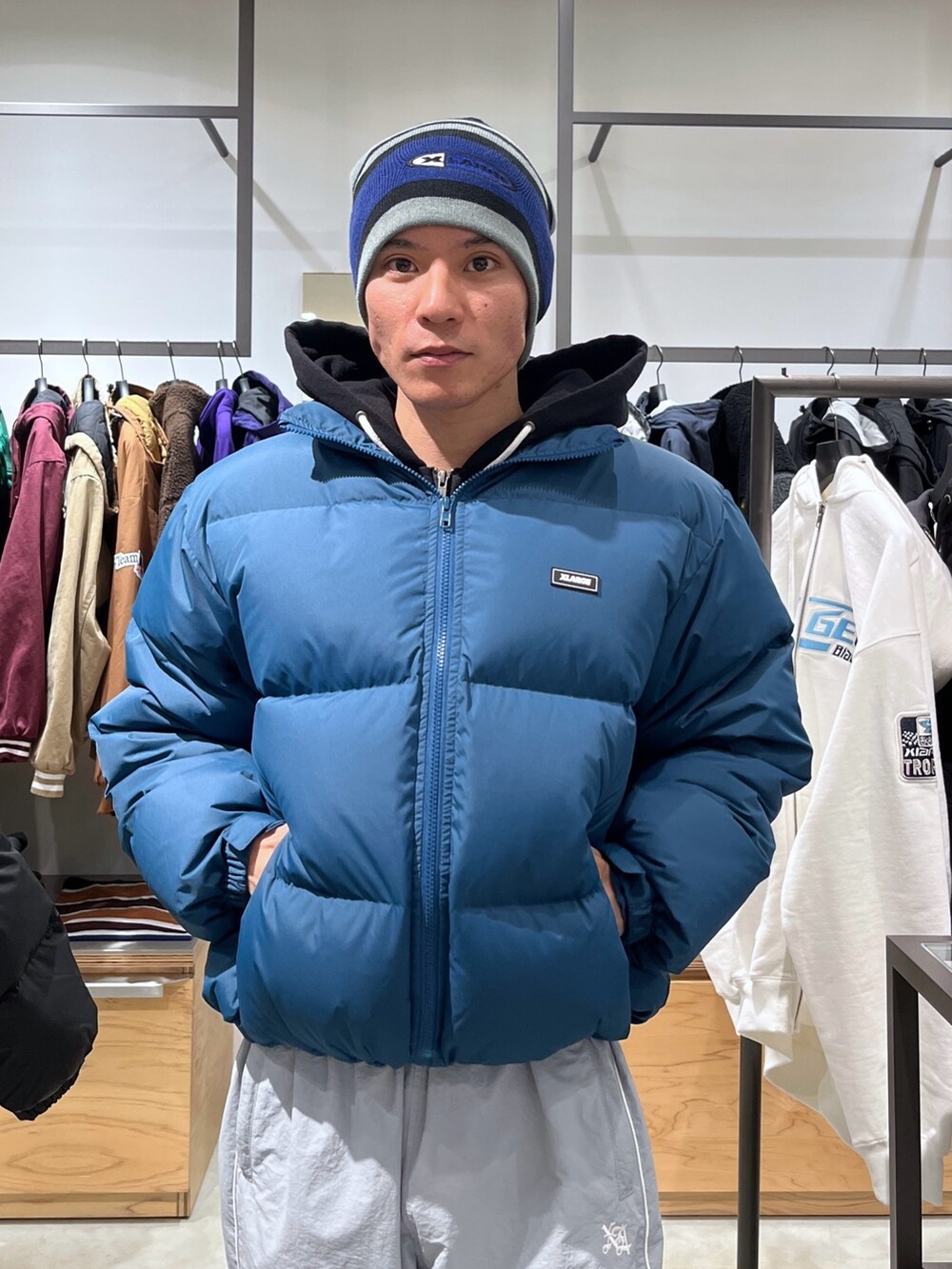 ブルー系のダウンジャケット/コート、グレー系のその他パンツ、ブラック系のニットキャップ/ビーニーを着用したメンズの秋コーディネートの6枚目の写真