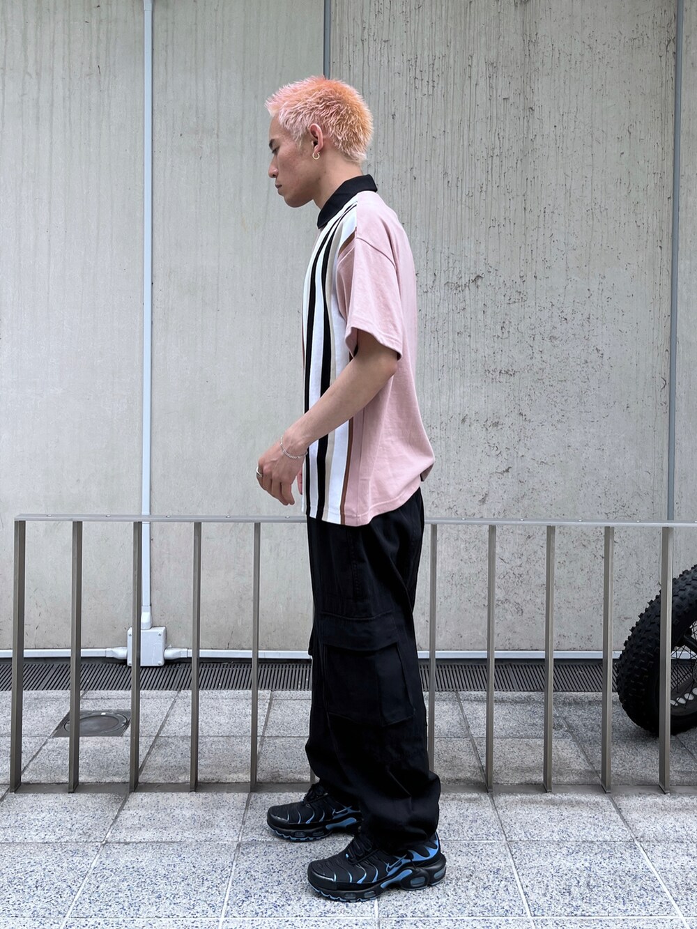 ピンク系のポロシャツ、ブラック系のカーゴパンツを着用したメンズの春コーディネートの2枚目の写真