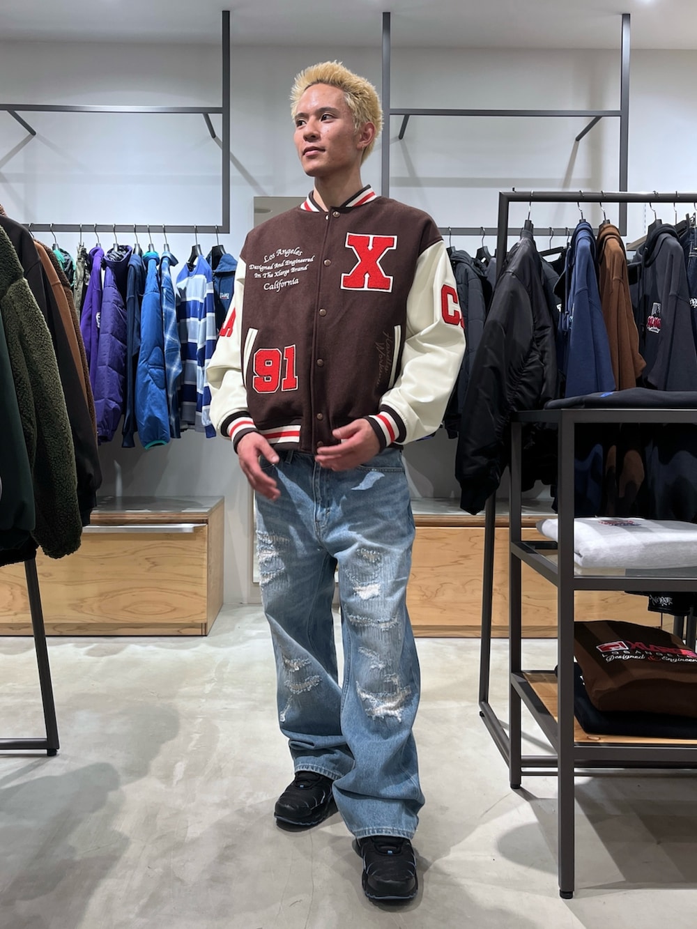 ブラウン系のスタジャン、ブルー系のデニムパンツを着用したメンズの秋コーディネートの2枚目の写真