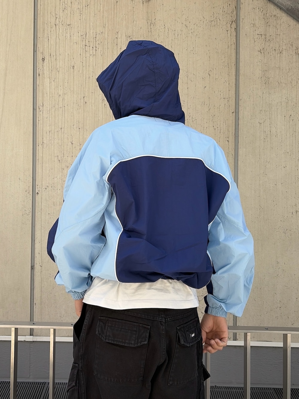 ブルー系のナイロンジャケット、ブラック系のカーゴパンツ、ブラック系のハットを着用したメンズの春コーディネートの7枚目の写真